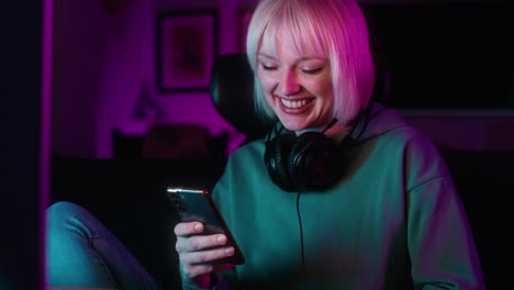 Cheerful-young-caucasian-woman-browsing-mobile-phone-while-a-break-during-playing-game-at-night-on-Desktop-P