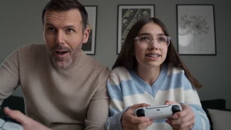 Front-view-of-caucasian-teenager-girl-and-her-father-playing-at-video-game-with-game-controller