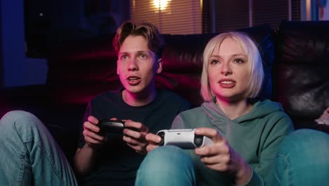 Young-caucasian-couple-playing-video-game-with-game-pads-while-sitting-on-floor