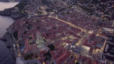 Dämmerungsantenne-über-Der-Beleuchteten-Altstadt-Von-Dubrovnik-Mit-Mittelalterlichen-Steinmauern