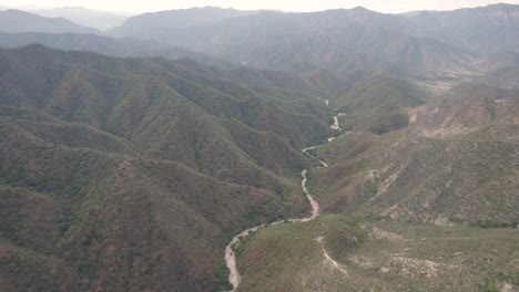 Winding-serpentine-path-carves-way-through-rugged-terrain-of-mountains,aerial