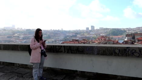 Handheld-shot-of-pretty-caucasian-woman-with-camera-and-a-phone-on-rooftop-in-Porto,-Portugal