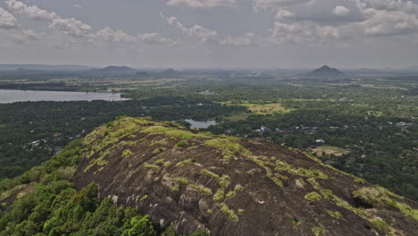 Dambulla-Sri-Lanka-Aerial-v5-reverse-flyover-Isigili-mountain-capturing-royal-cave-temple,-hillside-Uyanwatta-temple-and-surrounding-landscape-of-the-village-town---Shot-with-Mavic-3-Cine---April-2023