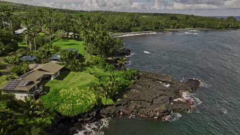 Hana-Maui-Hawaii-Aerial-v10-fly-along-rugged-shorelines-capturing-seaside-residential-areas,-dark-volcanic-rocks,-lush-greenery-and-scenic-hillside-landscape---Shot-with-Mavic-3-Cine---December-2022