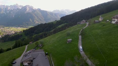 A-camper-van-drives-down-a-country-road-outside-Toblach,-Italy-in-this-drone-shot