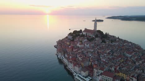 The-sun-sets-on-the-Croatian-island-city-of-Rovinj,-a-popular-tourist-destination,-as-the-camera-moves-backwards