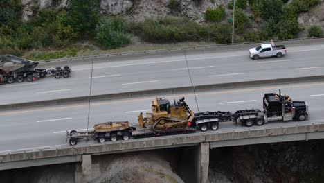 Heavy-Duty-Hauling-on-Coquihalla-Highway,-Excavator-and-Bulldozer-get-moved-on-steep-slope