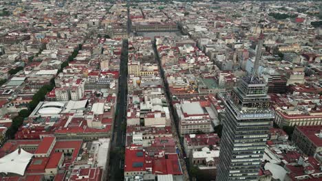 Drone's-eye-view,-Latinoamericana-Tower-and-Historic-Center,-with-the-Zocalo-in-the-distance-at-Mexico-City