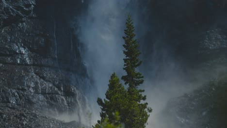 Eine-Filmische-Zeitlupenaufnahme-Riesiger-Kiefern-Und-Des-Riesigen-Und-Atemberaubenden-Takakkaw-Wasserfalls-Im-Hintergrund