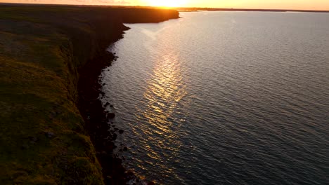 Tilt-of-the-cliffs-of-Iceland,-with-the-reflection-of-the-sunset-on-the-Atlantic-Ocean