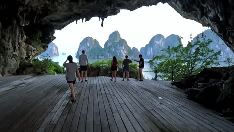 Tourists-walking-towards-the-view-of-Ha-Long-Bay-in-a-cave,-Vietnam