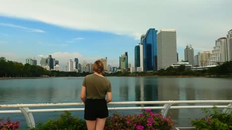 Touristin-Genießt-Die-Aussicht-Im-Benjakitti-Park,-Einem-Beliebten-Städtischen-Erholungspark-In-Bangkok,-Thailand-Mit-Wunderschönem-Blick-Auf-Die-Stadt-Und-Malerischen-Wanderwegen