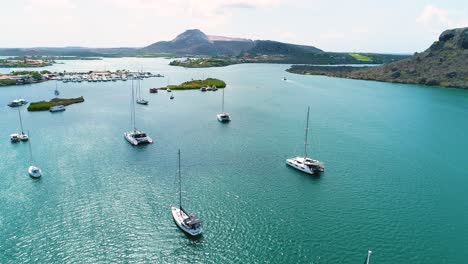 Barcos-Y-Catamaranes-Anclados-En-El-Agua-Al-Mediodía-En-Aguas-Españolas,-Tafelberg-Curacao-En-La-Distancia