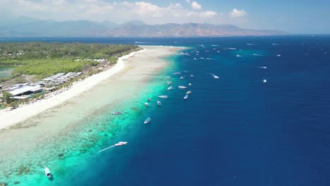 Aerial-panorama-view-of-the-beach-at-Gili-Meno-Island,-Indonesia,-in-sunny-weather-and-with-plenty-of-boats-in-the-crystal-blue-water