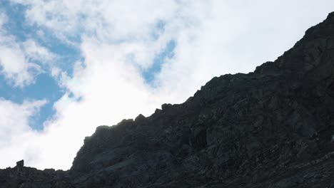 Cloudy-blue-sky-over-a-rock-ridge-of-a-cliff