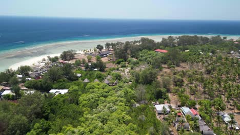 An-aerial-panorama-view-from-the-center-of-Gili-Meno-Island,-Indonesia,-looking-out-over-the-beach-and-the-beautiful-crystal-blue-ocean