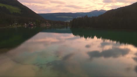 Drone-forward-shot-of-big-Lake-Dobbiaco-at-dusk-in-Toblacher-See,-South-Tyrol,-Italy