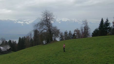 Cinematic-aerial-drone-beautiful-woman-dancing-Swiss-Alps-countryside-dance-jump-in-the-fog-hillside-sounds-of-music-scene-Thun-Bern-Interlocken-Switzerland-mountainside-circling-slowly-right-movement