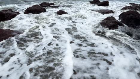 Closeup-shot-of-Waves-crashing-water-on-rocky-coastline-Cola-Beach-Goa-India-4K