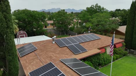 Drone-view-of-a-suburban-home-with-solar-panels,-set-against-a-backdrop,-lush-greenery-and-distant-mountains-in-Southwest-USA