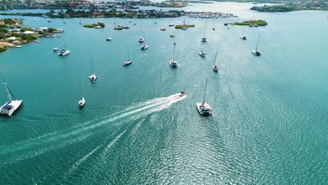 Boat-drives-across-Spanish-Waters-Curacao-at-midday-between-anchored-catamarans-and-sailboats