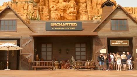 Pan-shot-of-tourists-standing-in-que-in-front-of-Uncharted-ride-in-the-Far-West-area-at-Port-Aventura-World-in-Salou,-Spain-on-a-sunny-day