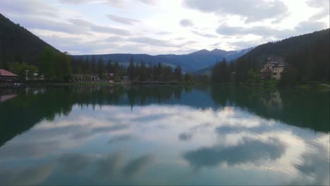 Drone-forward-shot-of-big-Lake-Dobbiaco-and-its-reflection-in-Toblacher-See,-South-Tyrol,-Italy