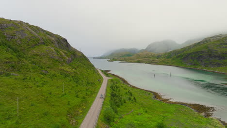 Campervan-driving-along-serene-fjord-in-Lofoten