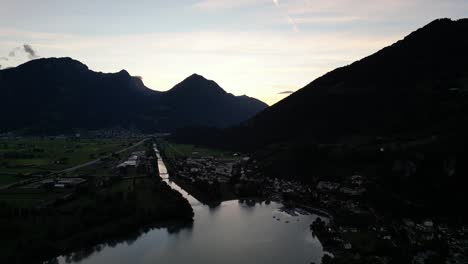 Atemberaubender-Drohnenblick-Auf-Dunkle-Berge-Mit-Grüner-Wiese-über-Dem-Walensee,-Schweiz-Am-Frühen-Morgen