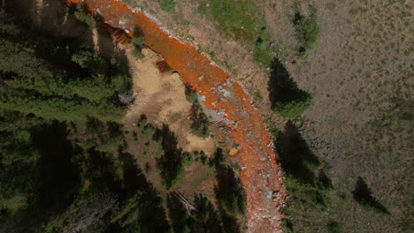 Aerial-cinematic-drone-orange-river-Cement-Creek-summer-high-altitude-Silverton-Ski-Area-resort-Telluride-Prospect-Gulch-Colorado-Rocky-Mountains-stunning-drive-looking-down-movement