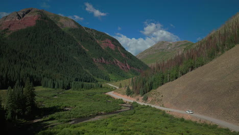 Aerial-drone-cinematic-Ice-Lake-Basin-trailhead-driving-van-county-road-summer-early-morning-Silverton-Telluride-Colorado-Rocky-Mountains-Aspen-forest-14er-peaks-forward-follow-from-side-motion