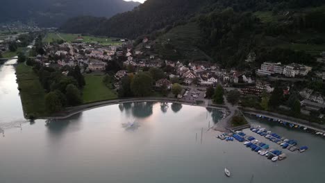 Vista-Aérea-De-Drones-Volando-Hacia-Atrás-De-La-Ciudad-De-Weesen-Con-Base-Cerca-De-La-Orilla-Del-Lago-Walensee,-Suiza
