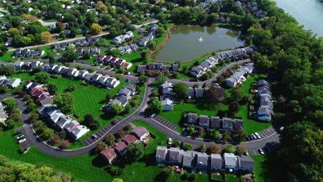 Orbital-View-over-Modest-Suburban-Neighborhood-with-grass-and-an-Lake-with-a-Fountain-in-a-Sunnyday,-Crystal-Lake-Illinois