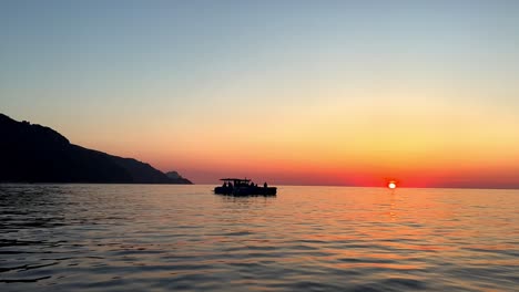 Silhouette-Eines-Navigationsbootes-Bei-Sonnenuntergang-Mit-Sonne-Am-Horizont