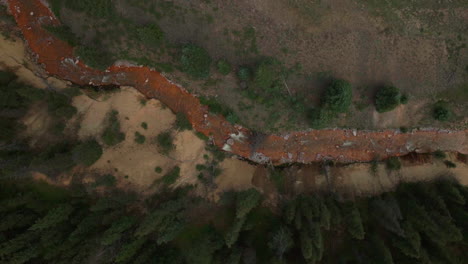 Aerial-cinematic-drone-orange-river-Cement-Creek-summer-high-altitude-Silverton-Ski-Area-resort-Telluride-Prospect-Gulch-Colorado-Rocky-Mountains-stunning-drive-looking-down-steam-movement