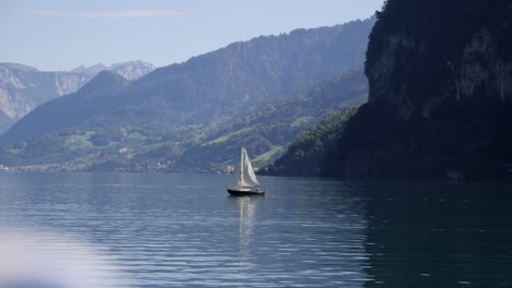 Cinematic-wide-shot-of-sailboat-on-lake-walensee,-alpine-backdrop,-slowmo