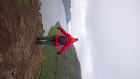 Free-traveler-woman-raising-her-arms-on-top-of-Klakkur-Mountain-in-Klaksvik,-Faroe-Islands