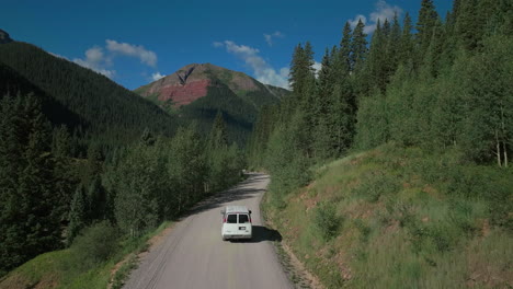 Aerial-drone-cinematic-Ice-Lake-Basin-trailhead-driving-van-county-road-summer-early-morning-Silverton-Telluride-Colorado-Rocky-Mountains-Aspen-forest-14er-peaks-forward-follow-motion