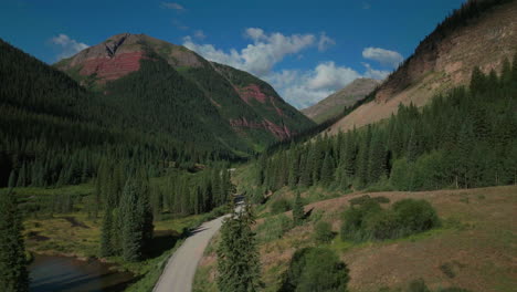 Aerial-drone-cinematic-Ice-Lake-Basin-trailhead-dirt-county-road-summer-early-morning-Silverton-Telluride-Colorado-Rocky-Mountains-Aspen-forest-14er-peaks-forward-motion