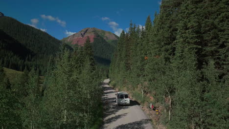 Aerial-drone-cinematic-Ice-Lake-Basin-trailhead-driving-van-county-road-summer-early-morning-Silverton-Telluride-Colorado-Rocky-Mountains-Aspen-pine-forest-14er-peaks-forward-follow-motion