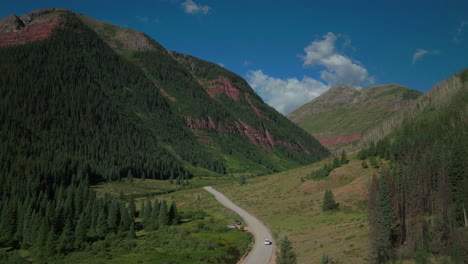 Aerial-drone-cinematic-Ice-Lake-Basin-trailhead-driving-van-county-road-by-river-summer-early-morning-Silverton-Telluride-Colorado-Rocky-Mountains-Aspen-pine-forest-14er-peaks-forward-follow-motion