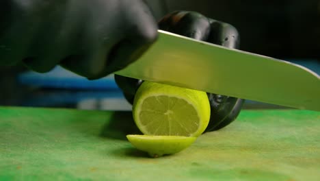Chef-slices-off-end-of-lemon-into-rounds-on-green-plastic-cutting-board