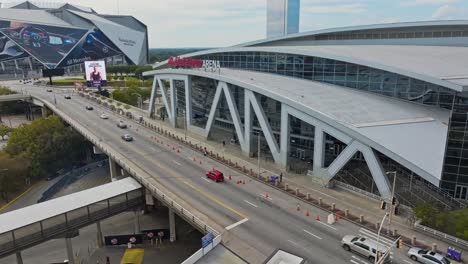 Cars-driving-in-road-in-front-of-State-Farm-Arena-and-Mercedes-Benz-Stadium-in-Atlanta-at-daytime---slow-forward-flight