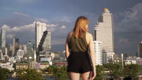 A-young-woman-points-out-towards-the-city-skyline-in-central-Bangkok