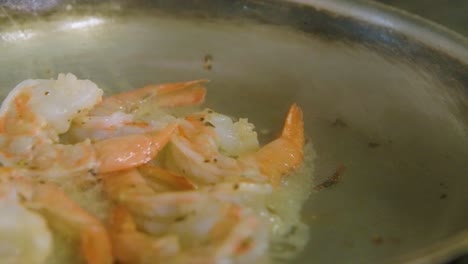 Detailed-close-up-of-gas-stove-flame-cooking-shrimp-in-butter-in-old-pan