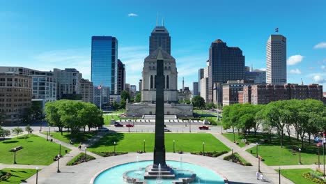 Sunny-Indianapolis-view-showcasing-the-Soldiers'-and-Sailors'-Monument,-flanked-by-modern-skyscrapers-and-a-vibrant-park