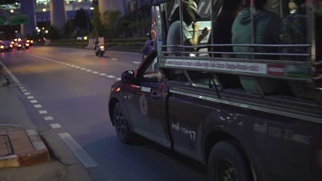 Un-Taxi-Público-Songthaew-Con-Lugareños-Pasa-Lentamente-Por-Una-Calle-De-Bangkok-Durante-La-Noche