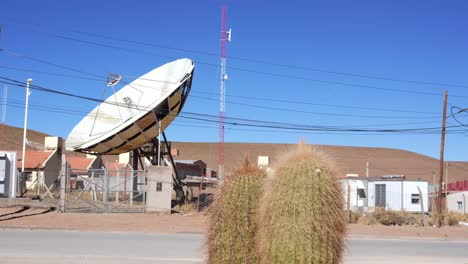 Large-parabolic-antenna-in-San-Antonio-de-los-cobres,-Argentina,-with-a-cactus-in-the-foreground