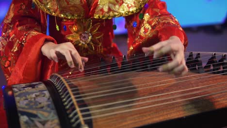 Una-Mujer-Con-Un-Vestido-Rojo-Adornado-Toca-Un-Instrumento-De-Cuerda-Tradicional-Tailandés-En-Bangkok