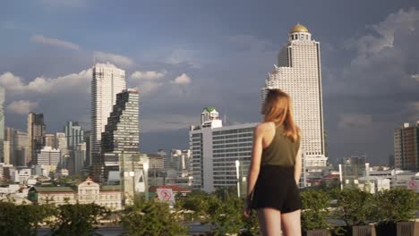 A-young-woman-is-admiring-the-blue-sky-and-the-city-skyline-of-downtown-Bangkok